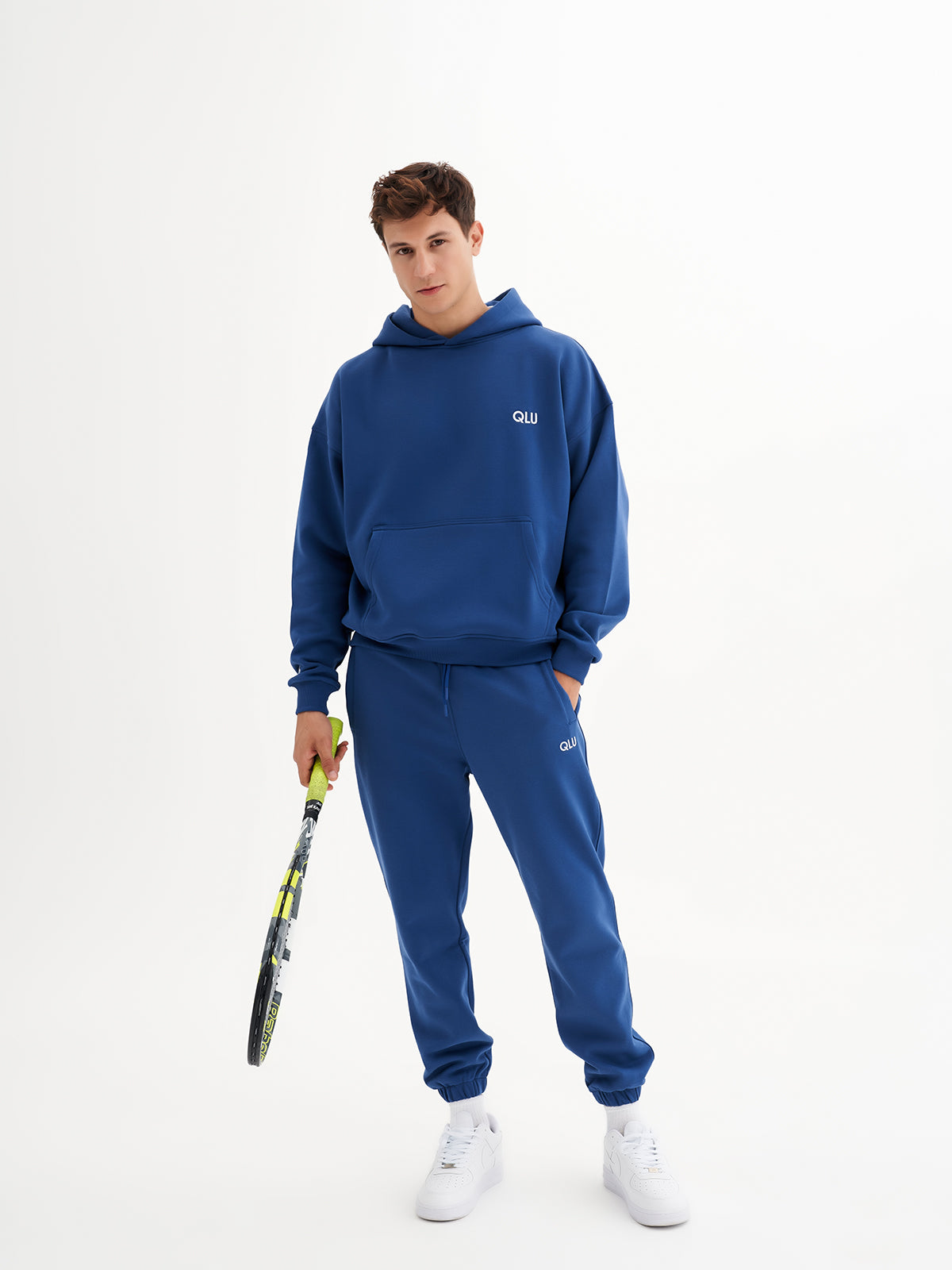 qlu bir tenis raketi tutan mavi bir hoodie giymiş bir adam