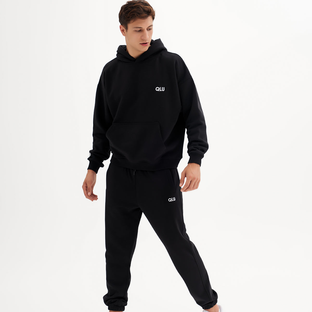 qlu siyah bir hoodie ve eşofman giyen genç bir adam